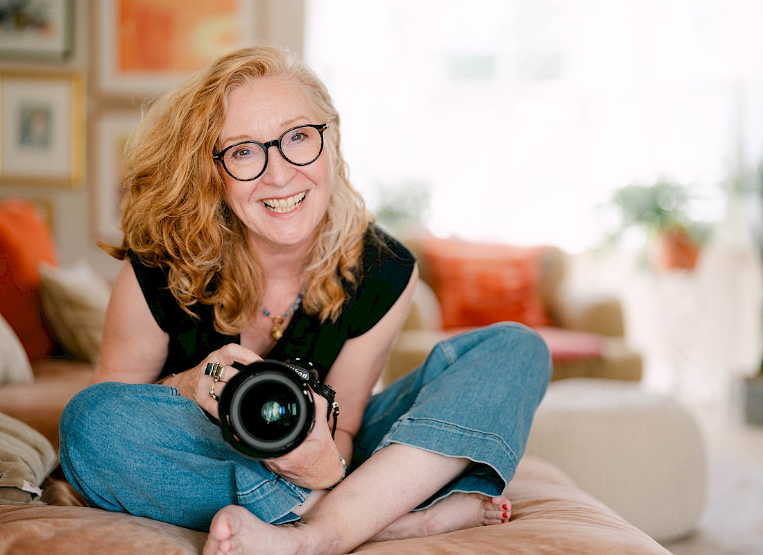 Photographer Bev Cunningham sat crossed legged holding camera